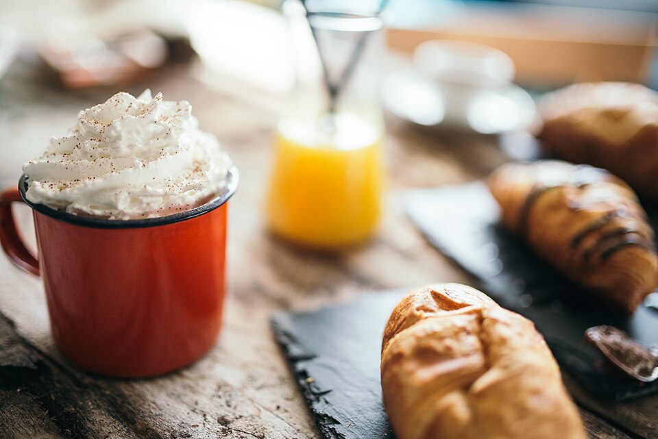 木のテーブルに置かれたコーヒーと焼き菓子