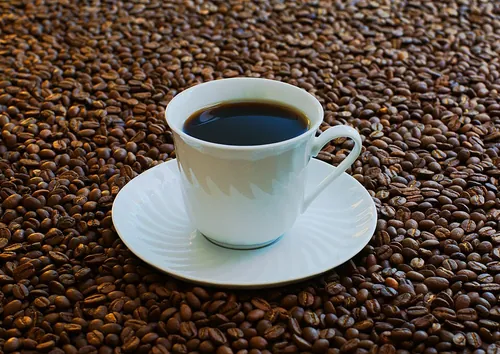 A cup of coffee surrounded by coffee beans